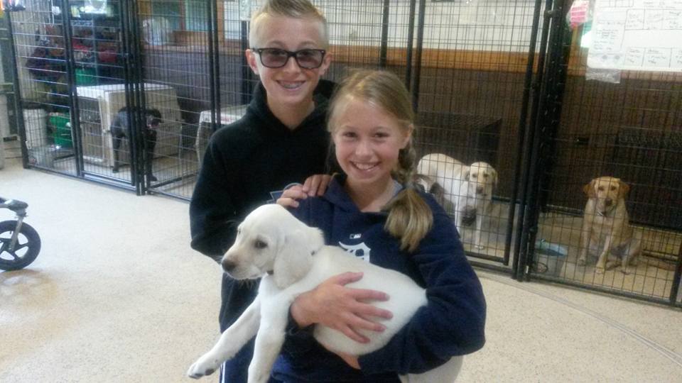 A boy and a girl holding a lab puppy